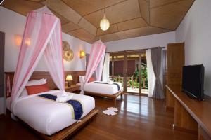 two beds in a room with a tv and a bedroom at PingChan Koh Phangan Beachfront Resort in Thong Nai Pan Yai