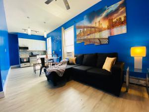 ein Wohnzimmer mit einer schwarzen Couch und einer blauen Wand in der Unterkunft NYC Oasis in Mott Haven