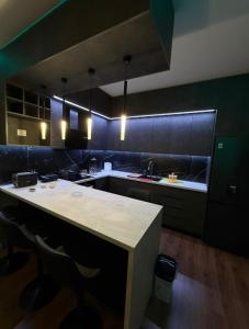 a kitchen with a white counter and black cabinets at Feel Home Apartment in Kamëz