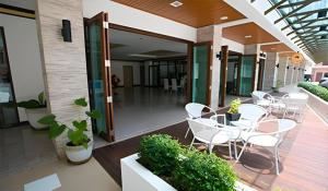 un patio avec des chaises et des tables blanches dans un bâtiment dans l'établissement The Capital Hotel, à Roi Et