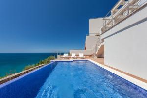 a swimming pool on the side of a house with the ocean at Villa Mar a Vista in Salema