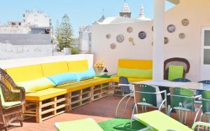 un balcone con panca gialla, tavoli e sedie. di BJB - Alojamentos a Olhão
