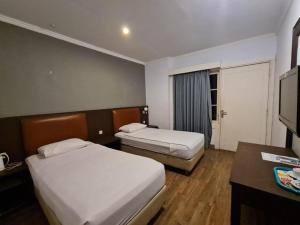 a hotel room with two beds and a television at Hotel Minahasa in Manado +67 photos