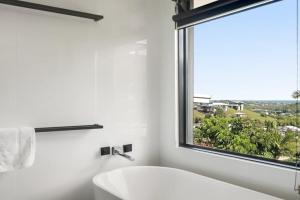 a bathroom with a white tub and a window at The Break in Lennox Head +6 photos