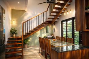 a kitchen with a wooden staircase and a table with chairs at PATHIRAMANAL Service Villas in Alleppey +2 photos