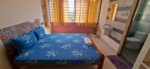 a small bedroom with a blue bed and a window at The Sparrow in Kanyakumari