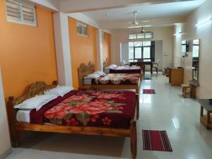 a bedroom with three beds in a room at Vinayaka Deluxe Lodge in Kushālnagar