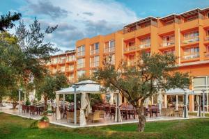 una vista exterior de un hotel con mesas y sombrillas en Residence Umag Plava Laguna, en Umag