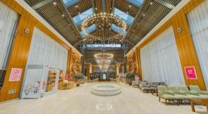 eine große Lobby mit Stühlen und einem Kronleuchter in einem Gebäude in der Unterkunft Deefly Yinrun Town Hotel in Deqing