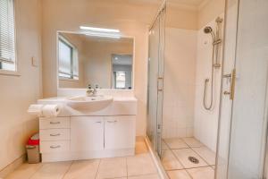 een witte badkamer met een wastafel en een douche bij Relaxing 3BR Home by Wattle Downs Reserve in Auckland +27 foto's