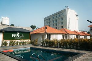 a hotel with a swimming pool in front of a building at Fenna Resort And Spa, coorg in Kushālnagar
