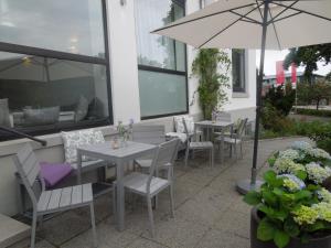 eine Terrasse mit Tischen, Stühlen und einem Sonnenschirm in der Unterkunft Nice n´Nordic 2 in Hamburg