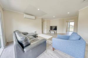 een woonkamer met een bank en een tafel bij Relaxing 3BR Home by Wattle Downs Reserve in Auckland
