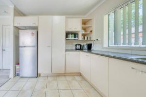 een keuken met witte kasten en een koelkast bij Relaxing 3BR Home by Wattle Downs Reserve in Auckland