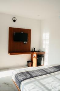 a bedroom with a bed and a tv on the wall at Fenna Resort And Spa, coorg in Kushālnagar