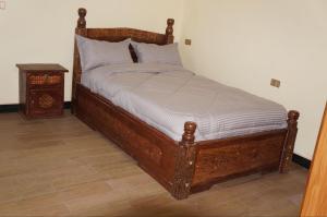 un letto con struttura in legno in una stanza di Kings Land Hotel a Lalībela