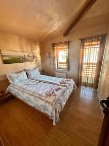 a large bed in a room with two windows at Chepelare Holiday Guest House in Chepelare
