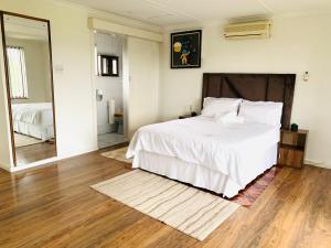 a bedroom with a white bed and a mirror at Ezendalo Guest House in Pinetown +15 photos