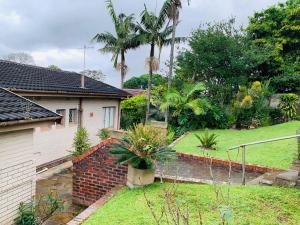 a house with a brick wall and a yard at Ezendalo Guest House in Pinetown