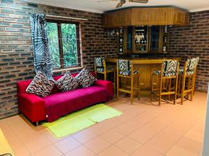 a living room with a red couch and a bar at Ezendalo Guest House in Pinetown