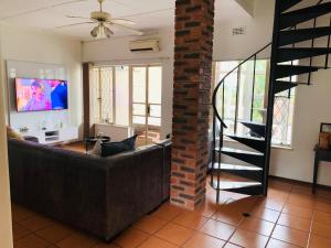 a living room with a couch and a brick wall at Ezendalo Guest House in Pinetown