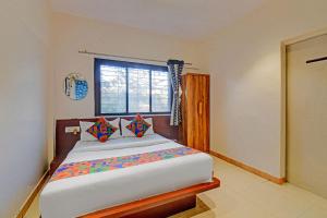 une chambre avec un grand lit avec une fenêtre dans l'établissement FabHotel Nisarg Villa, à Pune