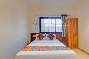une chambre avec un grand lit avec une fenêtre dans l'établissement FabHotel Nisarg Villa, à Pune