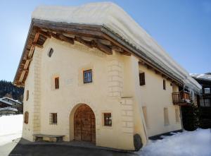 a building with an archway in the snow at Chesa Chamuera in La Punt-Chamues-ch