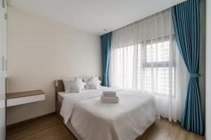 une chambre avec un lit blanc avec des rideaux bleus et une fenêtre dans l'établissement Homie Apartmant l Vinhomes Grand Park, à Hô-Chi-Minh-Ville