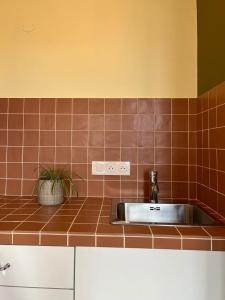 a kitchen with a stainless steel sink and brown tiles at Le Petit Logis in Marcigny +1 photo