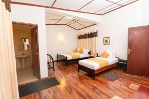 a hotel room with two beds and a bathroom at Anaya Villa in Nuwara Eliya