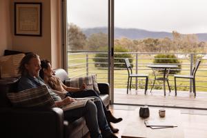 two people sitting on a couch in a room with a balcony at Eco-Luxe @ Mount Avoca in Avoca