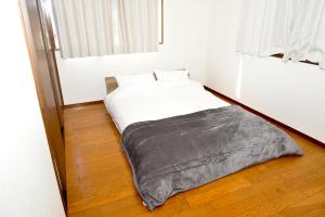 a bed sitting on a wooden floor in a room at 高岡ゆるり家 Yururi-Ya in Takaoka