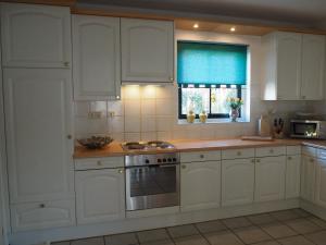 a kitchen with white cabinets and a window at Villa Julia 148 in Callantsoog