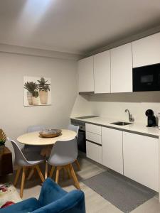 een keuken met witte kasten en een tafel en stoelen bij Aveiro Studio Alboi in Aveiro