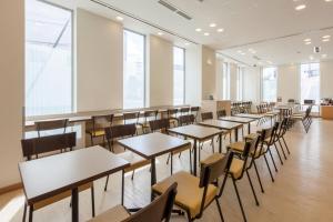 a row of tables and chairs in a room with windows at Comfort Hotel Kushiro in Kushiro