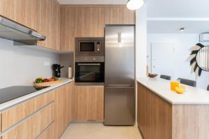 a stainless steel refrigerator in a kitchen with wooden cabinets at Villa Trilux, Infinity Pool, Jacuzzi, BBQ in Salobre