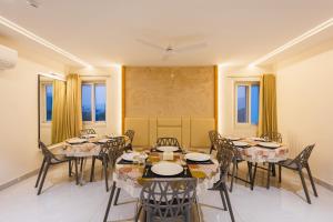 ein Esszimmer mit Tischen, Stühlen und Fenstern in der Unterkunft Treebo Ss Residency Gandhi Nagar in Vijayawāda