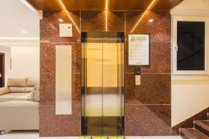 ein gläserner Aufzug in einem Raum mit einer Couch in der Unterkunft Treebo Ss Residency Gandhi Nagar in Vijayawāda + 39 Fotos