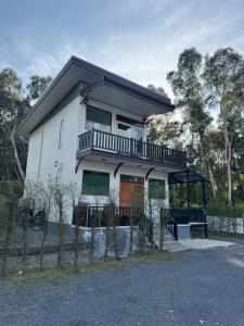 a white house with a balcony on top of it at Woodland Residence in Wok Tum