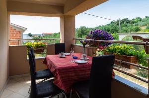a table and chairs on a balcony with a view of a garden at Sobe Gora in Posedarje