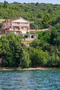 a house on a hill next to the water at Sobe Gora in Posedarje
