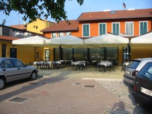 a patio with tables and white umbrellas in front of a building at Hotel Ristorante Morus in Burago di Molgora