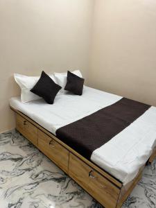 ein Bett mit schwarzen und weißen Kissen darauf in der Unterkunft Flats in city center, next to NEXUS MALL in Mysore