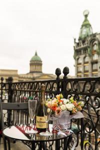 a table with a bottle of wine and flowers on a balcony at Novaya Istoria in Saint Petersburg