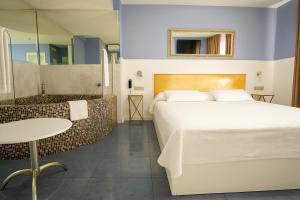 a bedroom with a bed and a table and a tub at Hotel Consentido in Granollers