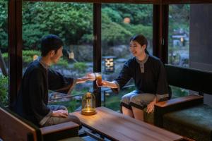 Ein Mann und eine Frau sitzen mit einem Drink an einem Tisch. in der Unterkunft RYOKAN OQOQ-Tamai Bekkan in Matsue