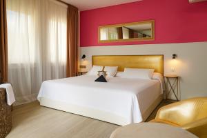 una camera da letto con un letto bianco e uno specchio a parete di Hotel Consentido a Granollers