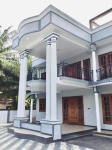a large white building with columns and a balcony at Rika Guest House in Kokkuvil East