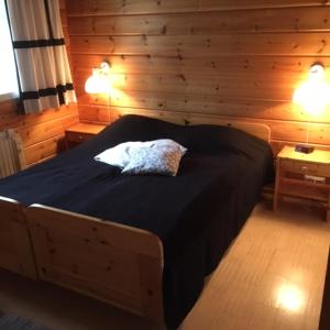 アカスロンポロにあるYlläs Suistotie Cottageのベッド1台(ナイトスタンド2台、ランプ2つ付)が備わる木造の部屋です。